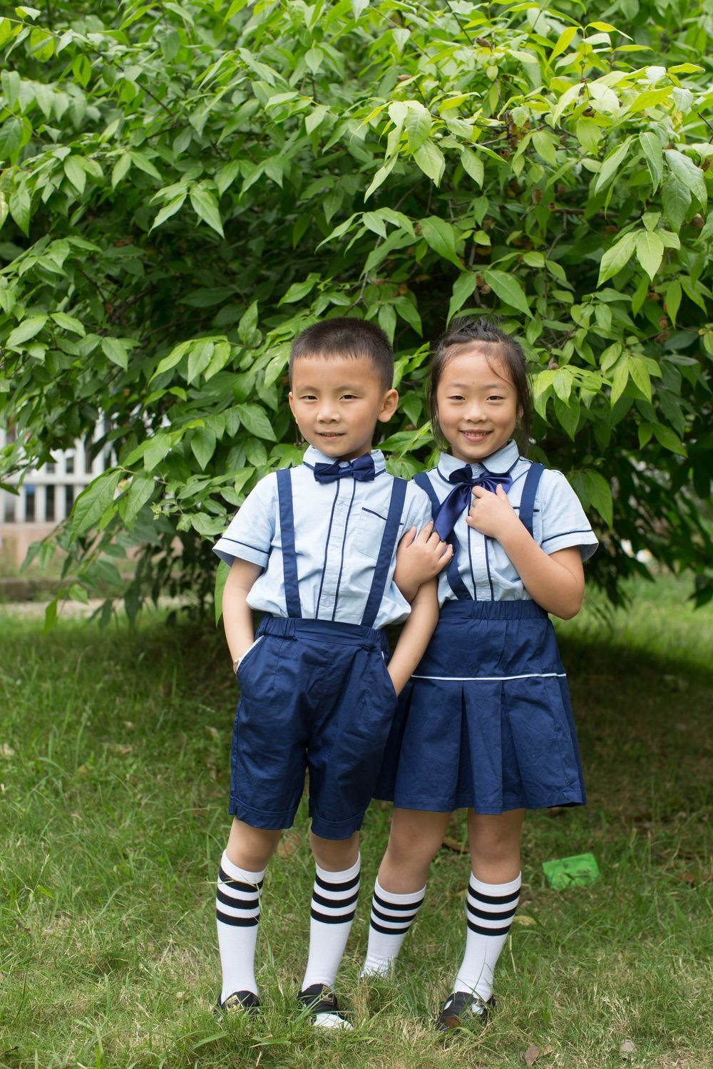 Two children wearing a blue and white school uniform